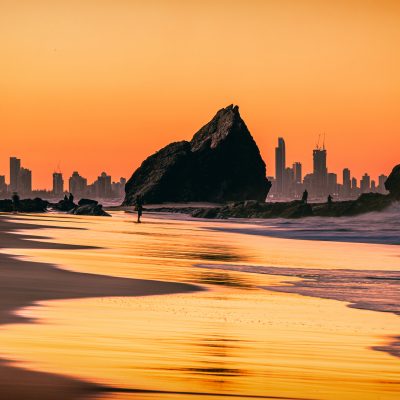 The sunset view of the Currumbin Beach in the twilight and the urban skyline of  Gold Coast in the dusk